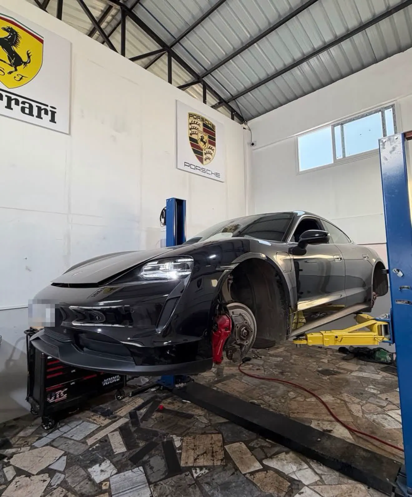 Atölyede kaldırıcıdaki siyah Porsche Taycan